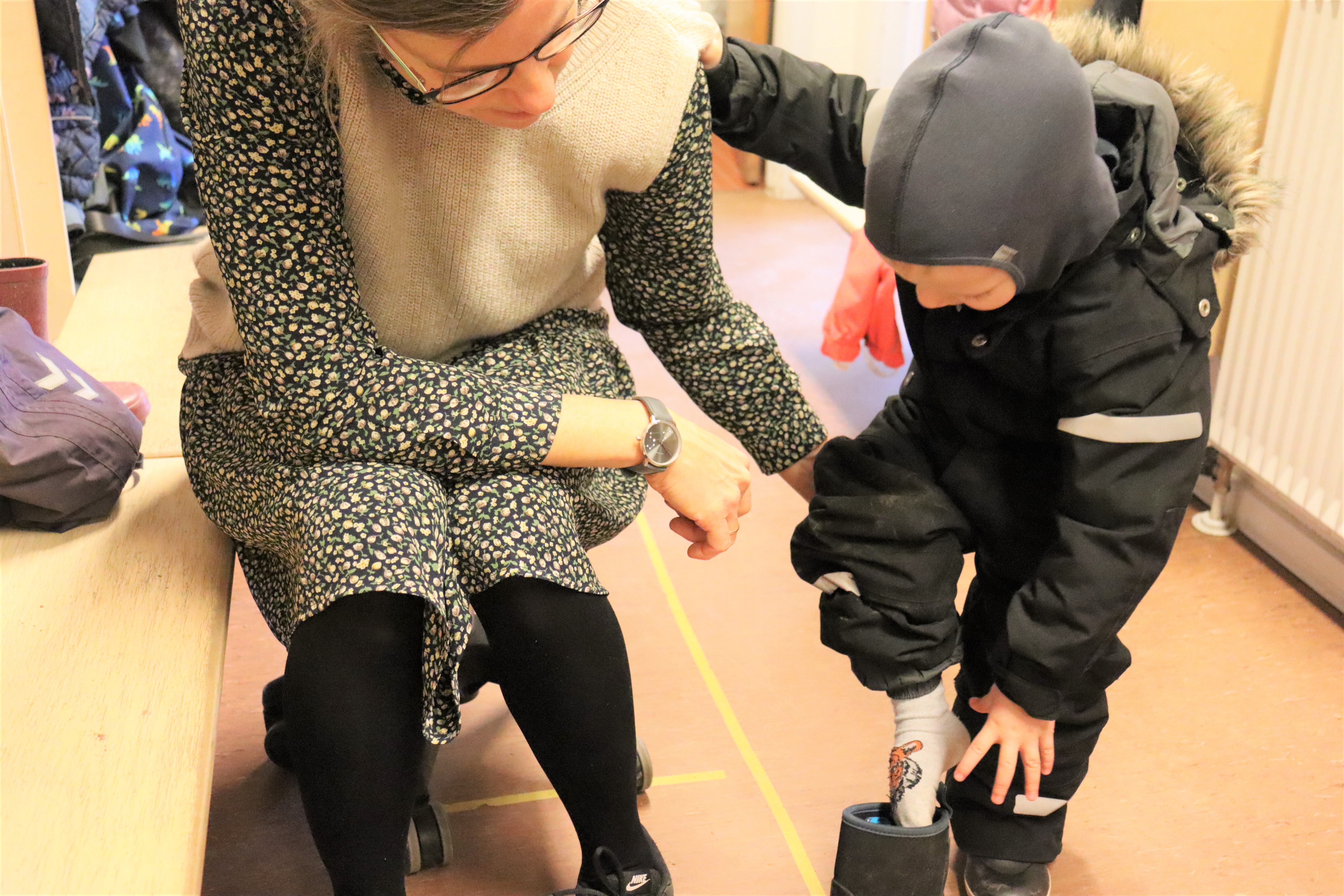 Pædagog hjælper barn med at tage støvler på