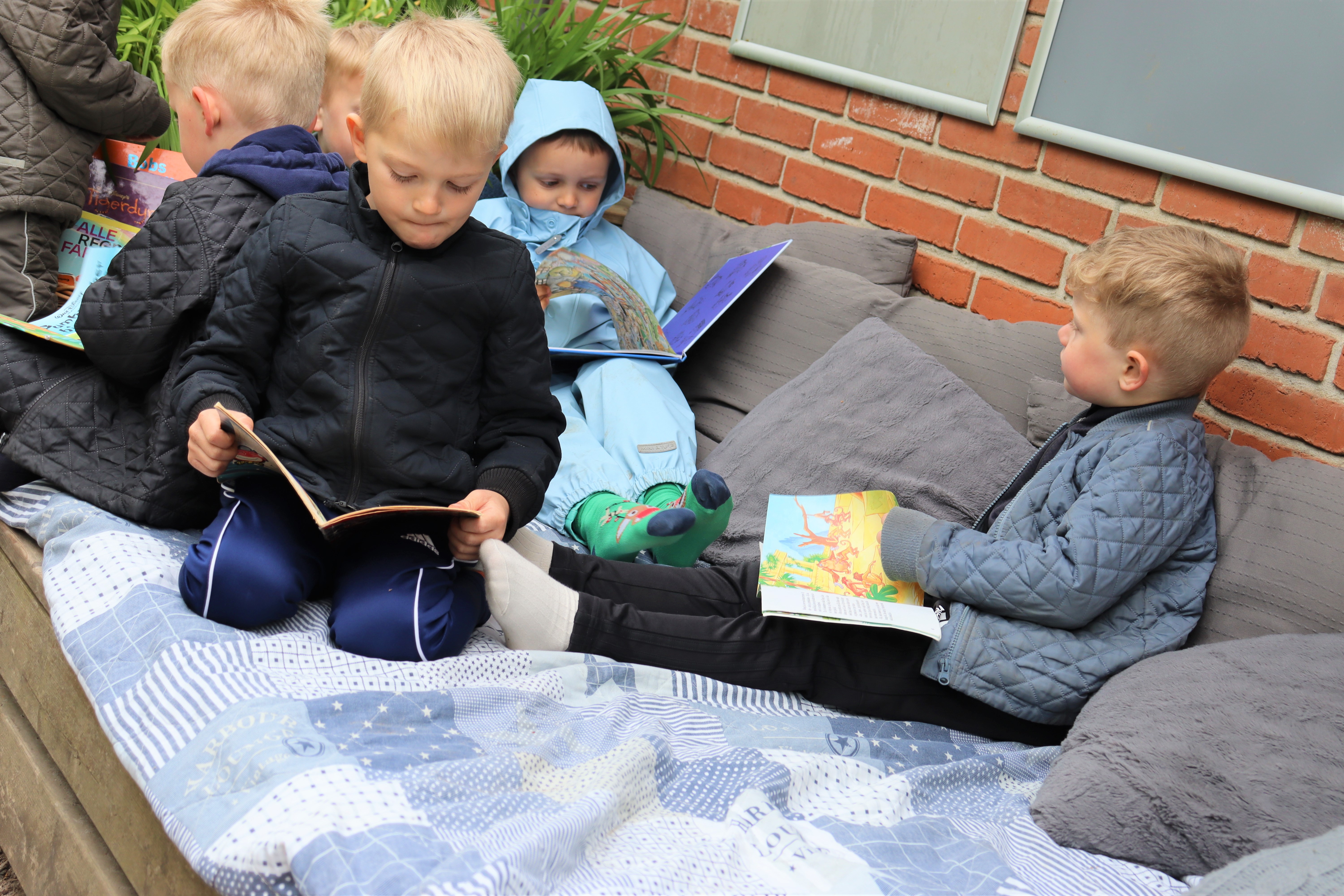 Børn læser udenfor på hynder